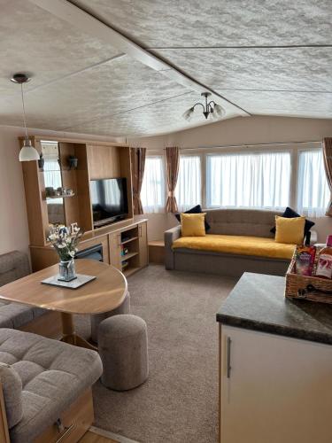 a living room with a couch and a table at Phoenix caravan hire, Trecco bay in Porthcawl