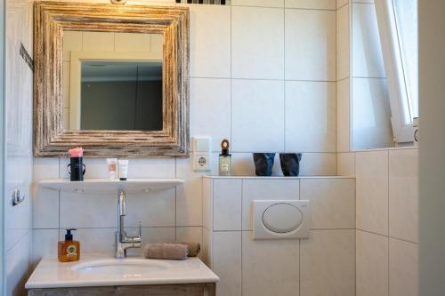 a bathroom with a sink and a mirror at Antares Spiekerooger Gästehaus-Sonnengartenbalkon Nord - Wohnung 5 in Spiekeroog