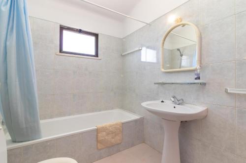 uma casa de banho com um lavatório, uma banheira e um espelho. em Casa Prensa em Carvoeiro
