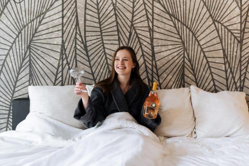 a woman sitting on a bed holding a toothbrush at Cosmopolite Hotel Nieuwpoort-Bad in Nieuwpoort