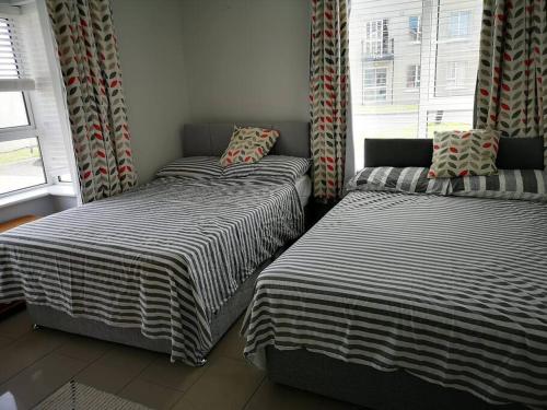 two twin beds in a room with a window at The Sandhills, Tramore Beach in Tramore