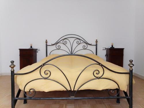 an iron bed with a yellow bedspread at villa gesualda in Bagno di Romagna