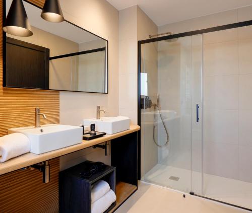 a bathroom with two sinks and a shower at Nuvō Hotel Boutique in Oviedo