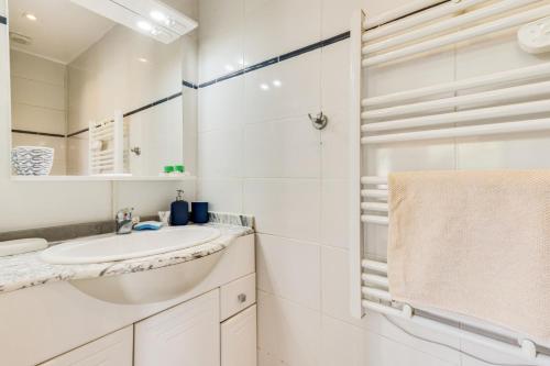 uma casa de banho branca com um lavatório e um espelho em Studio calme proche Paris avec terrasse privative et jacuzzi en option em Palaiseau