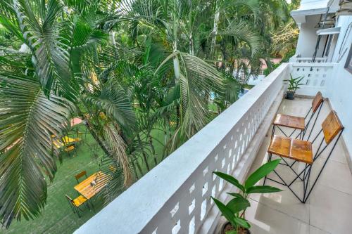 a balcony with chairs and tables and palm trees at The Boho, Vagator Beach Goa Near Thalassa in Anjuna