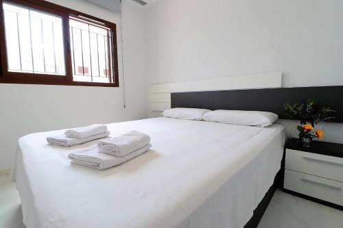 Un dormitorio blanco con una cama blanca grande con toallas. en Casa del sur, en San Juan de los Terreros