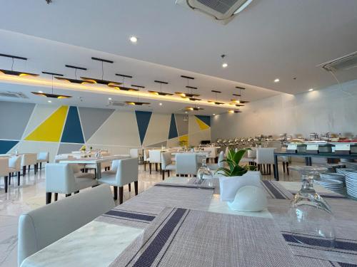 Golden Peak Hotel & Suites powered by Cocotel في مدينة سيبو: غرفة طعام مع طاولات وكراسي بيضاء