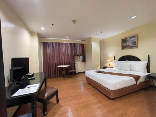 Golden Peak Hotel & Suites powered by Cocotel في مدينة سيبو: غرفة في الفندق بها سرير ومكتب وبه جهاز كمبيوتر