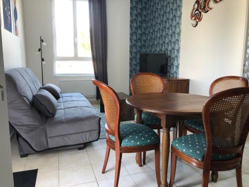 un salon avec une table, des chaises et un canapé dans l'établissement Votre oasis de détente : Appartement flambant neuf, 1 chambre, 4 couchages à Aubigné-racan, à Aubigné-Racan