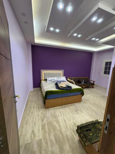 a bedroom with a bed and a purple wall at بالقرب من مدينتي شقه مميزه جديده ثلاث غرف وحمامين in Badr