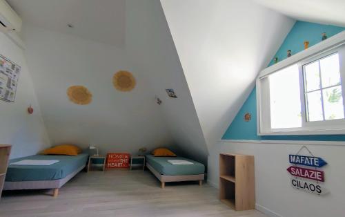 a attic room with two beds and a window at Eskal Péi - Auberge de Jeunesse & Chambres d'hôtes in Étang-Salé