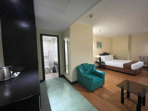 a hotel room with a bed and a blue chair at Golden Peak Hotel & Suites powered by Cocotel in Cebu City