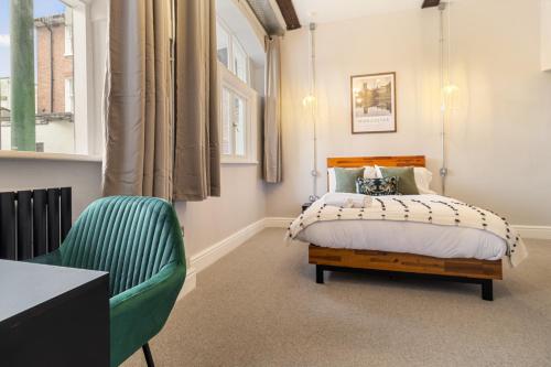 a bedroom with a bed and a green chair at WhiskAwayStays - Shaw Mews - Apartment 3 in Worcester