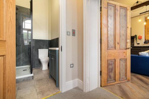 a bathroom with a toilet and a wooden door at WhiskAwayStays - Shaw Street - Character city centre apartment in Worcester