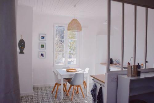 eine weiße Küche mit einem weißen Tisch und Stühlen in der Unterkunft Maison de vacances de charmes au bord de la mer in Saint-Brevin-les-Pins