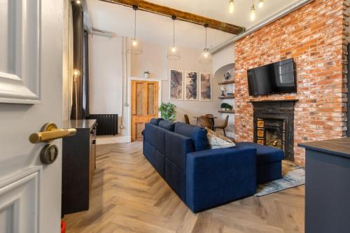 a living room with a blue couch and a brick wall at WhiskAwayStays - Shaw Mews - Apartment 3 in Worcester