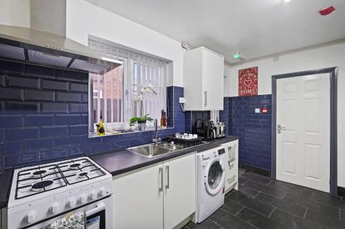 a blue and white kitchen with a washer and dryer at Stunning 5Bed House in Birmingham contractors also in Birmingham