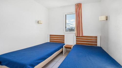 une petite chambre avec deux lits et une fenêtre dans l'établissement PRIMAVERA 321 - Appt lumineux 4 pers, au Cap d'Agde