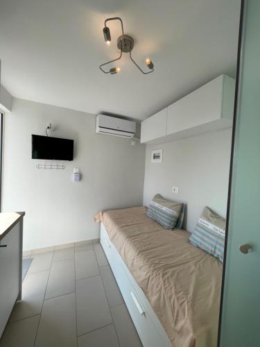 een kleine kamer met een bed en een televisie bij Roof top studio in Patra