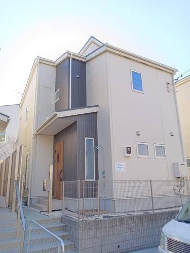 a white building with a fence in front of it at 湘南片瀬HOME in Fujisawa