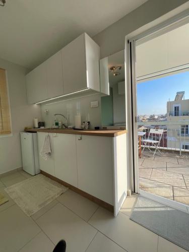 a kitchen with white cabinets and a large window at Roof top studio in Patra