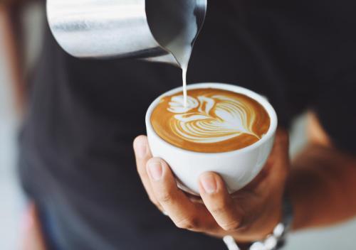 a person is holding a cup of coffee with a spoon at The Angel Hotel in Alton
