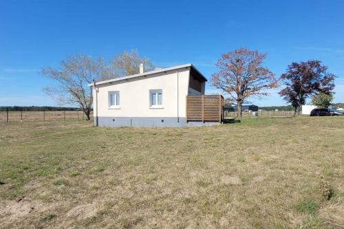 a small white house in a field at Petite maison sur aérodrome in Cosne-Cours-sur-Loire