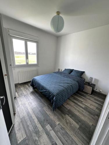 une chambre avec un lit avec une couette bleue dans l'établissement Petite maison sur aérodrome, à Cosne-Cours-sur-Loire