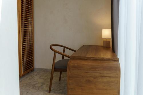 a wooden desk with a chair and a lamp at Sunny Cuddles in Canggu