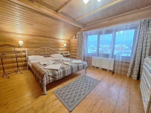 sypialnia z łóżkiem i dużym oknem w obiekcie Khytir Falchi w mieście Mikuliczyn