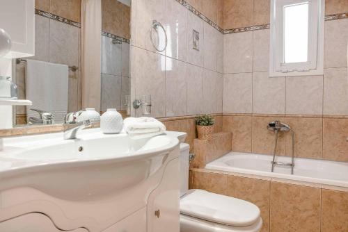 a bathroom with a toilet and a sink and a tub at Villa Marita in Spathíon