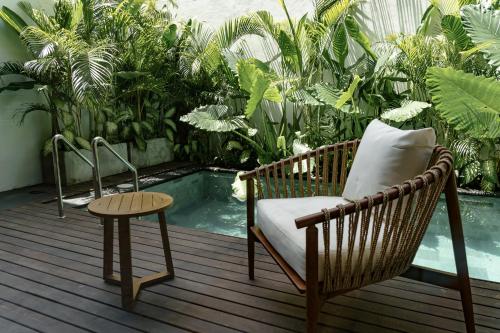 a chair and a table on a deck with a pool at Sunny Cuddles in Canggu
