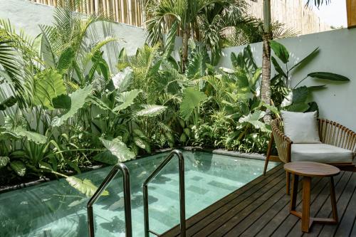 a balcony with a pool and a chair and plants at Sunny Cuddles in Canggu