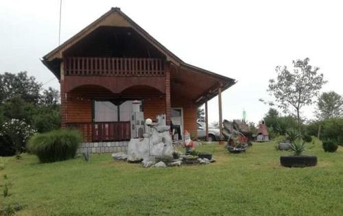 a small house with a porch on a grass field at Kuća za odmor Anita in Generalski Stol