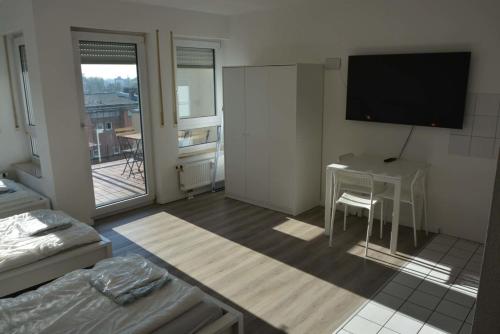 ein Wohnzimmer mit einem Schreibtisch und einem TV an der Wand in der Unterkunft ATRIUM - gemütliches Apartment BÜRGERMEISTER in Ludwigshafen am Rhein