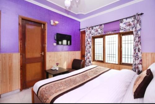 een slaapkamer met een groot bed met paarse muren bij Hotel Hill view in Shimla