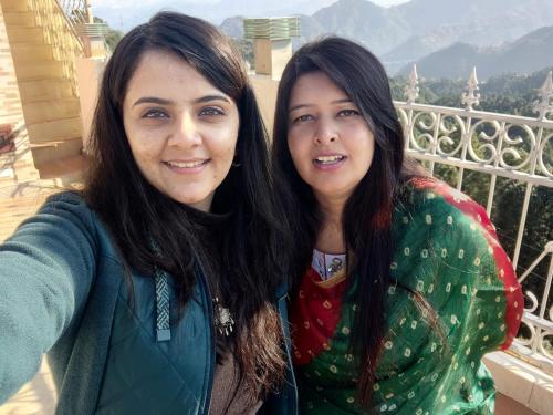 twee vrouwen die naast elkaar staan op een balkon bij Hotel Hill view in Shimla