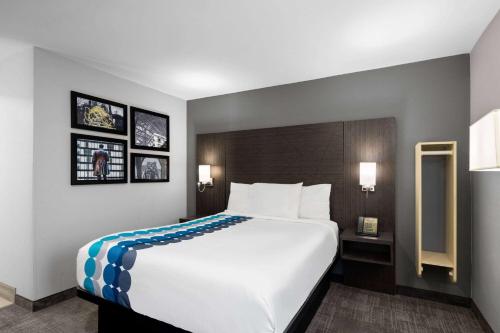 インディアナポリスにあるラ キンタ イン インディアナポリス エアポート エグゼクティブ ドライブの大きなベッドと壁に絵が飾られたホテルルームです。