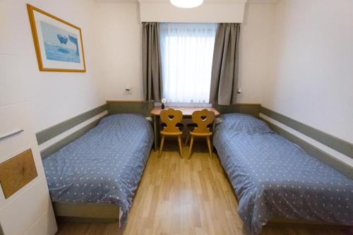 Cette chambre comprend 2 lits, une table et une fenêtre. dans l'établissement Ferienhaus Nr 4, Kategorie Premium L, Feriendorf Hochbergle, Allgäu, à Bichel
