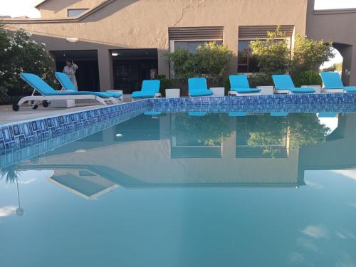 a swimming pool with blue lounge chairs next to a house at Ein Gedi Premier Lodge in Kimberley