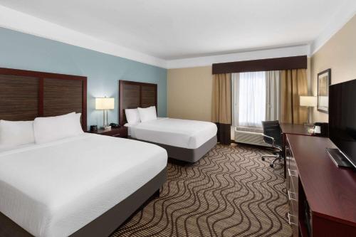 a hotel room with two beds and a flat screen tv at La Quinta by Wyndham Houma in Houma