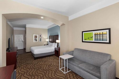 a hotel room with a couch and a bed at La Quinta by Wyndham Houma in Houma