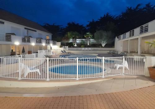 una valla blanca alrededor de una piscina por la noche en RÉSID'AZUR APPARTEMENT T2-PMR- Piscine privée, en Saint-Jean-de-Monts