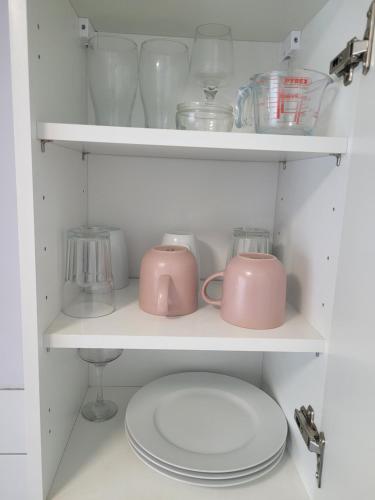 a shelf with bowls and other glass items on it at RentUnique The Sissinghurst in Three Bridges