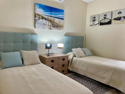 Un dormitorio con 2 camas y una mesa con lámparas. en Apartamento Cordobán Torre, en Córdoba