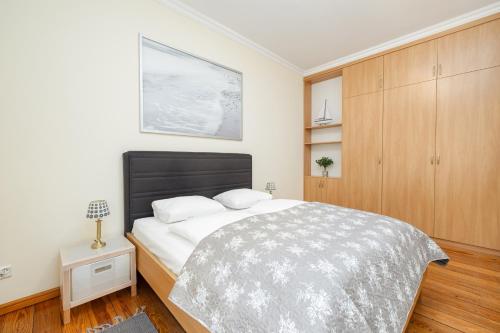 a bedroom with a large bed and a wooden cabinet at Charming Apartment Located near the Promenade in Świnoujście by Renters in Świnoujście