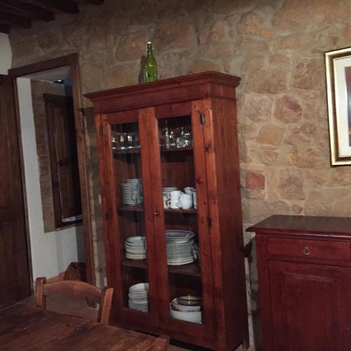 a wooden cabinet with plates and cups in it at Villa Fonte all'Oppio con area piscina recintata in Pienza