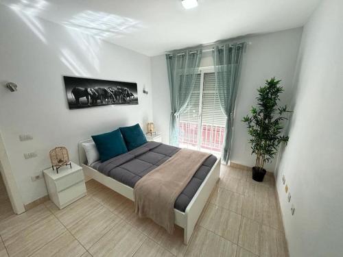 a bedroom with a bed with blue pillows and a window at Villa Buenavistas in Adeje