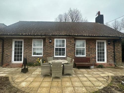 een stenen huis met een patio met een tafel en stoelen bij Cosy Cottage in Crawley