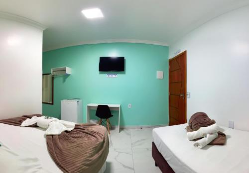 two beds in a room with a blue wall at Pousada Mar de Luna in Penha